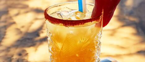 A glass with a red rim, ice cubes, and a red chili pepper on the rim.