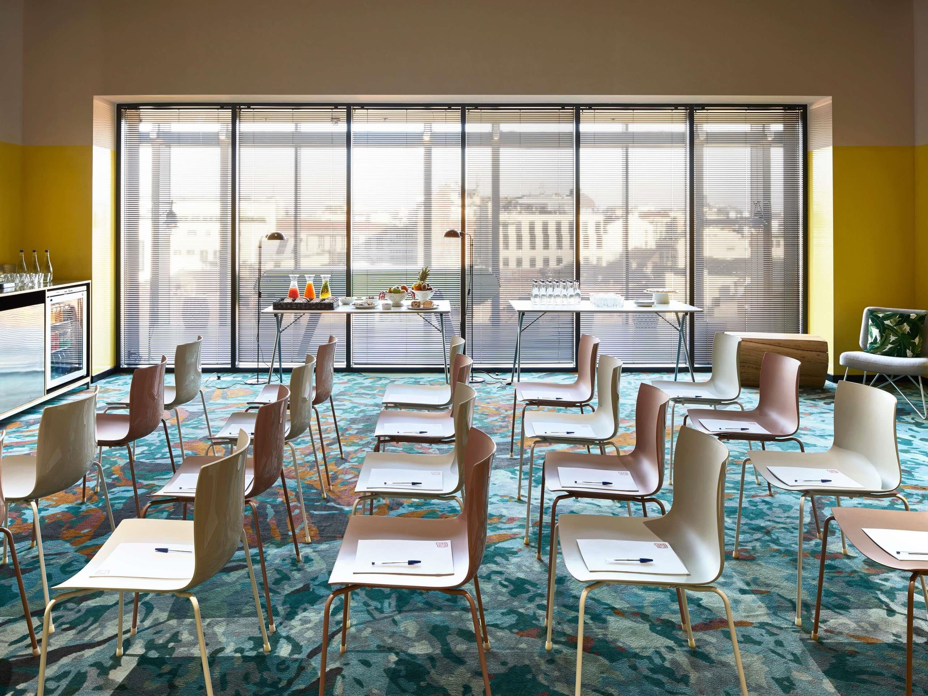 Une salle de conférence dotée d’une grande fenêtre, d’une table où sont disposées des boissons et de chaises disposées pour une réunion.
