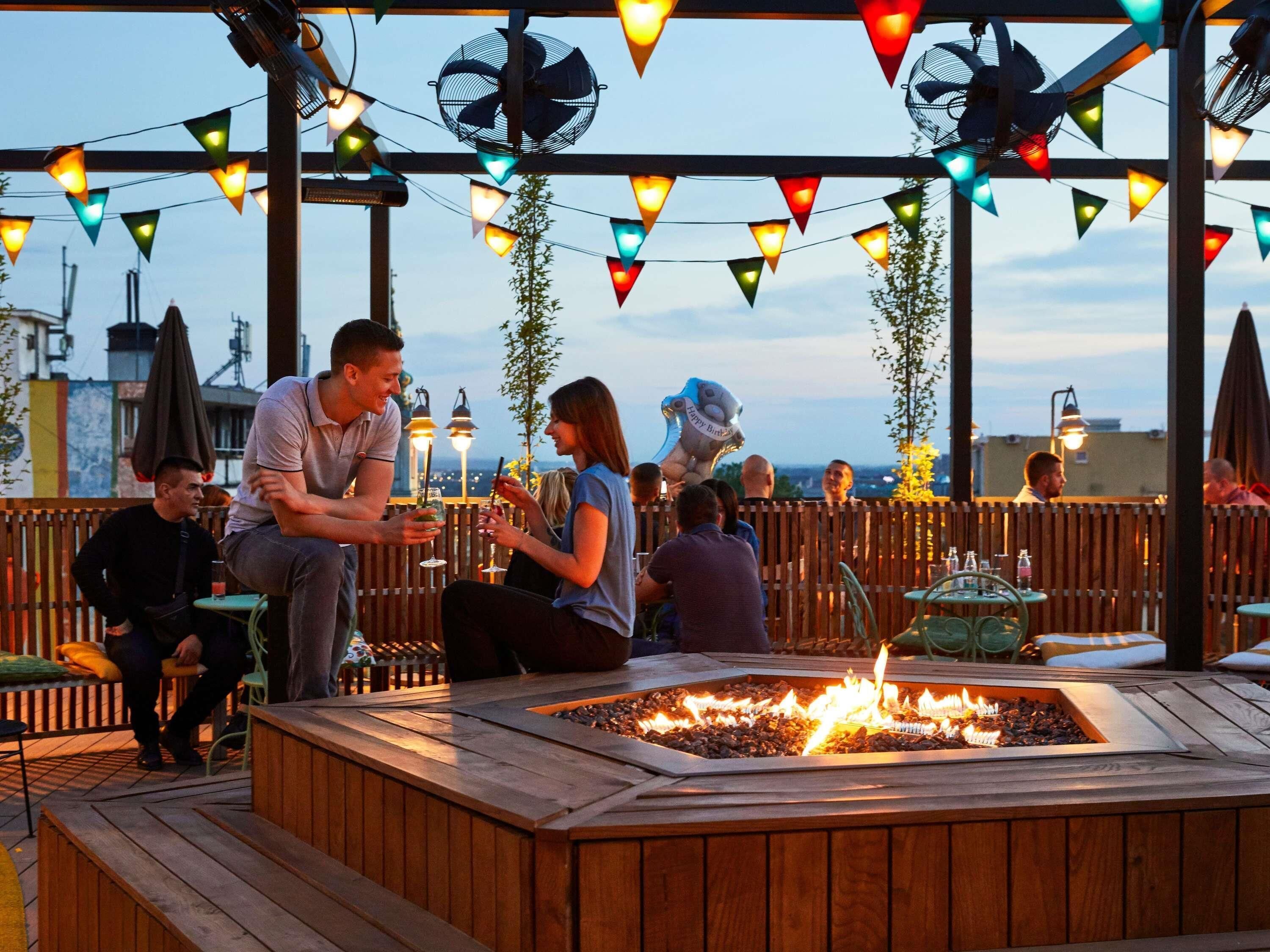 An outdoor seating area with a fire pit, wooden deck, and string lights.