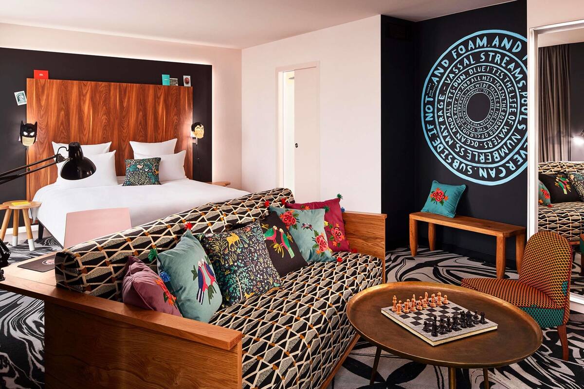 Ein modernes Hotelzimmer mit einem großen Bett, einer Sitzecke, einem Schachtisch und einer Wand mit kreisförmigem Design.