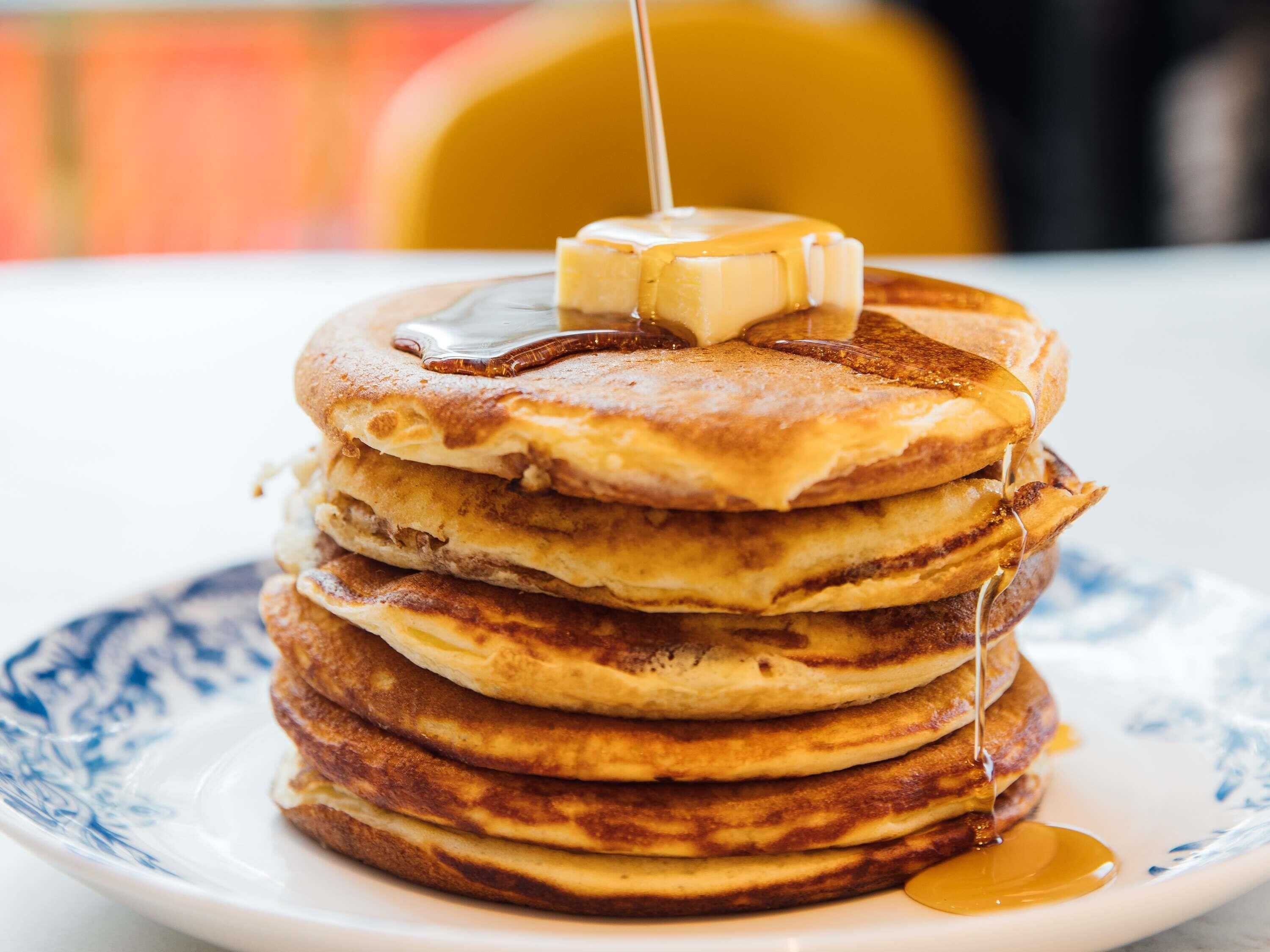 Una pila de tortitas con jarabe sobre un plato.