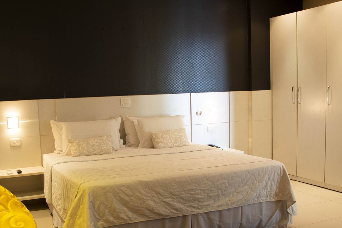 Een slaapkamer met een bed, nachtkastjes, een kledingkast en een vloerkleed.