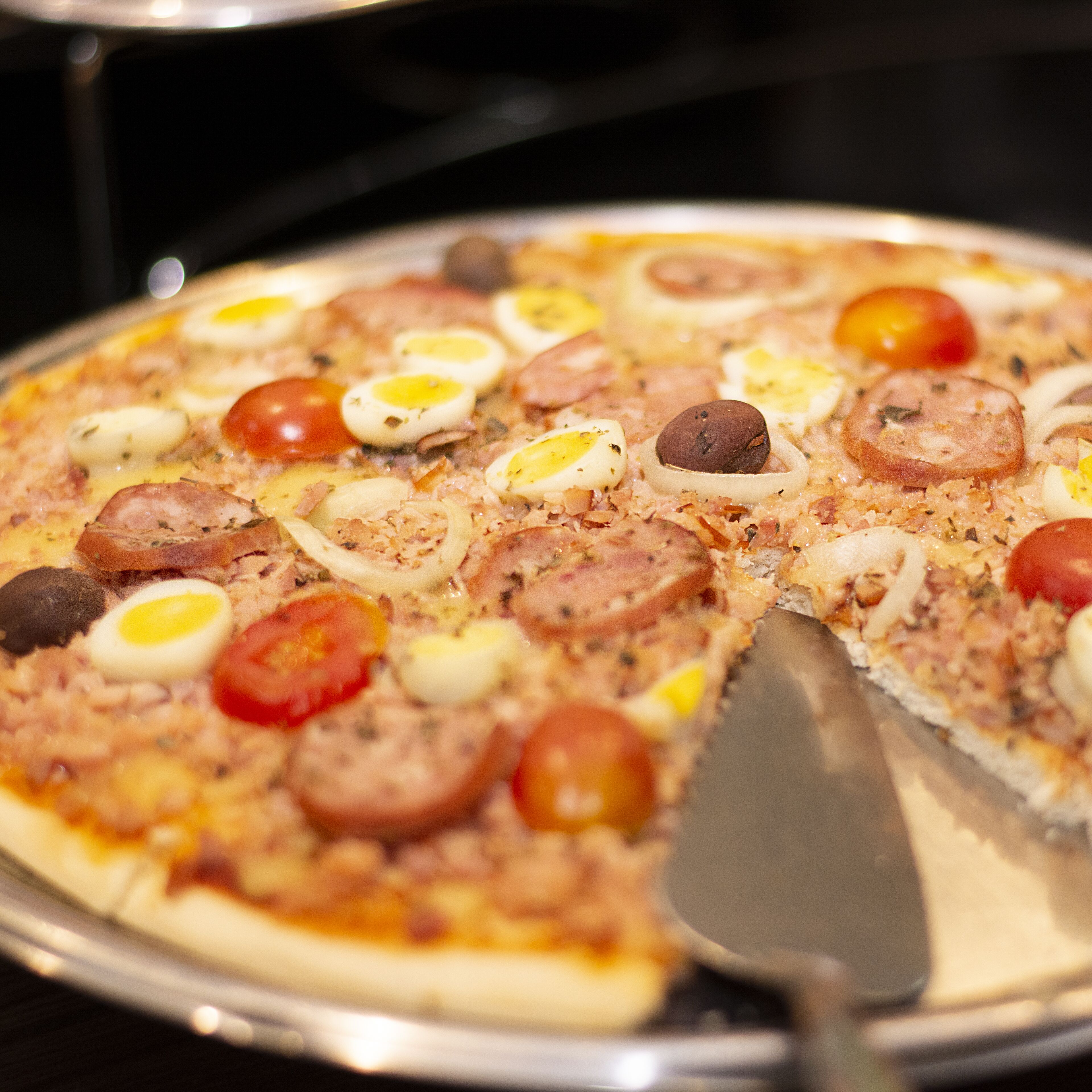 A pizza with various toppings on a metal tray.