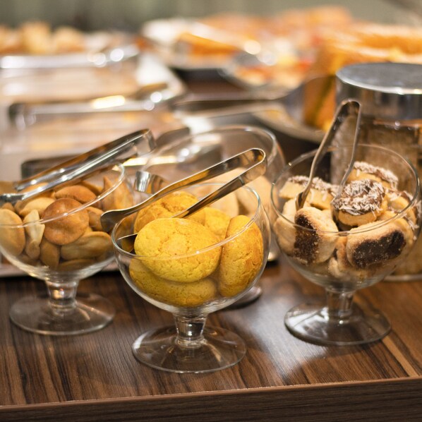 A buffet table with various desserts in glass bowls, including cookies and pastries. - Golden Plaza Hotel by Easy Class (Porto Velho)