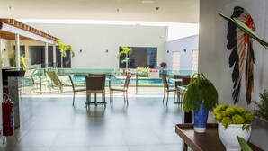 A spacious indoor area with a pool, seating by the pool, and potted plants. - Golden Plaza Hotel by Easy Class (Porto Velho)