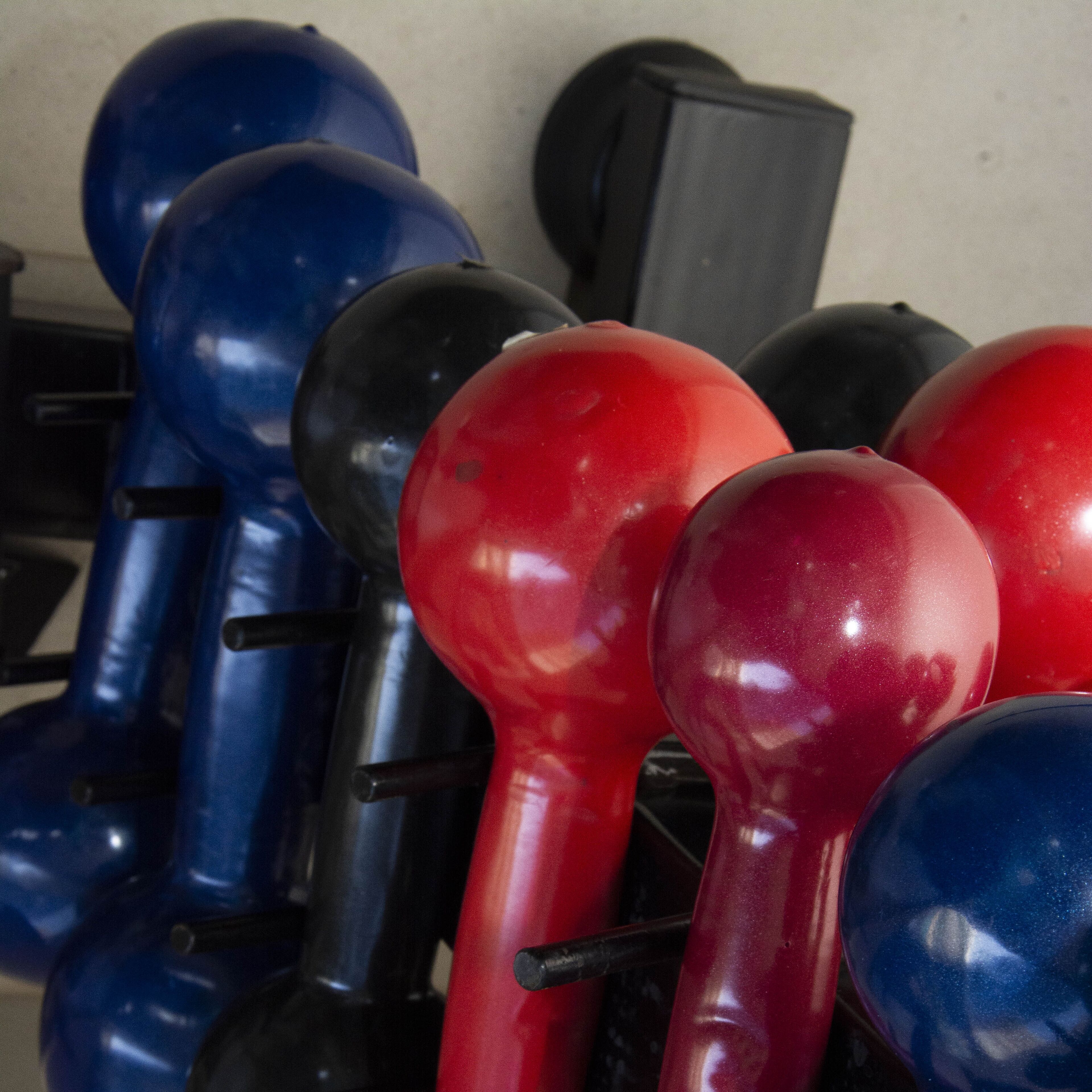 A collection of black and red kettlebells with handles, arranged on a rack.