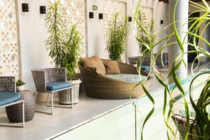 A lounge area with wicker furniture, potted plants, and a glass partition. - Golden Plaza Hotel by Easy Class (Porto Velho)