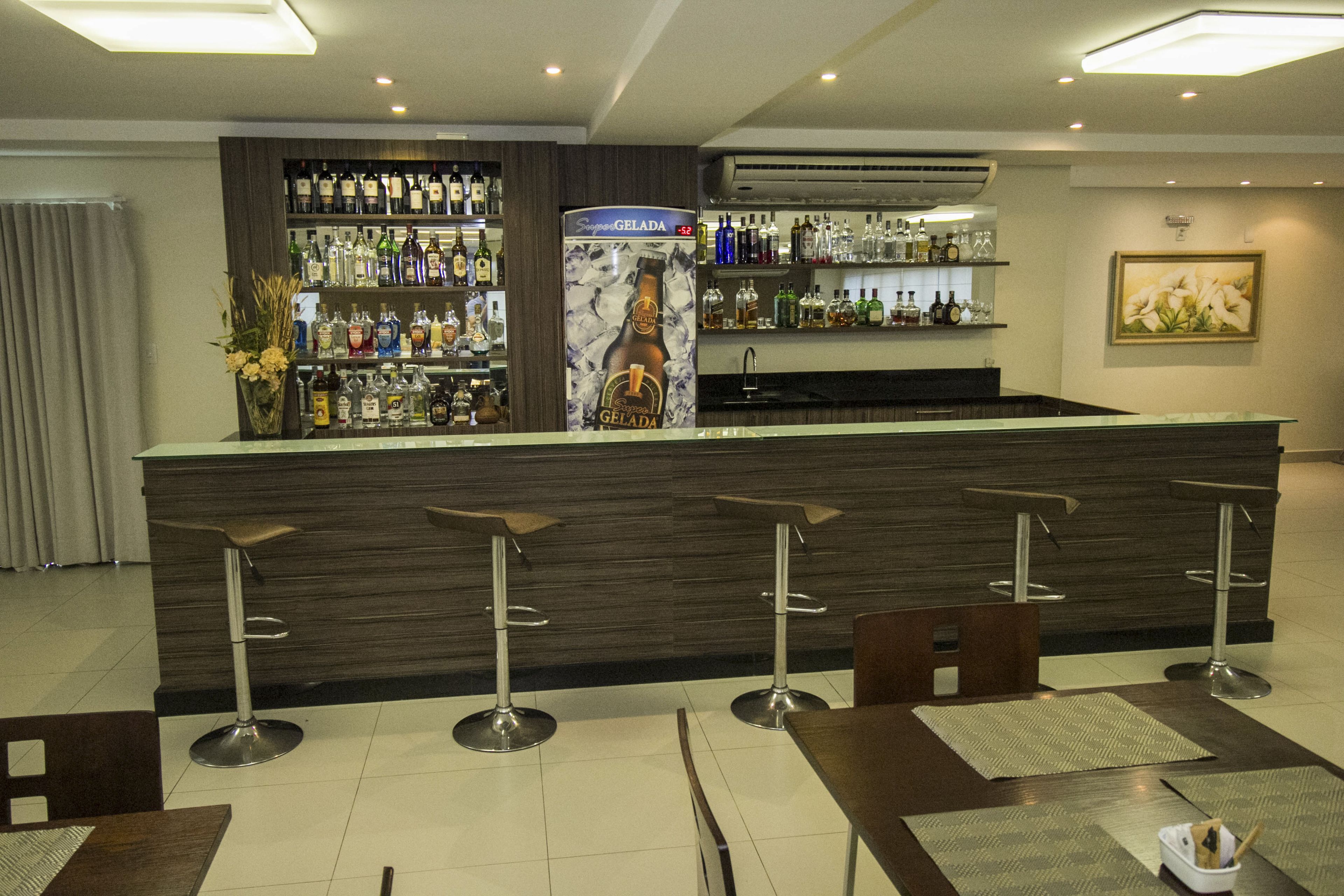 A bar area with a counter, stools, and a variety of bottles.
