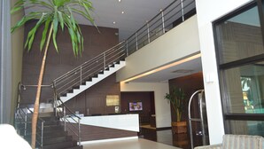 A modern lobby with a staircase, a reception desk, and a large potted plant. - Golden Plaza Hotel by Easy Class (Porto Velho)