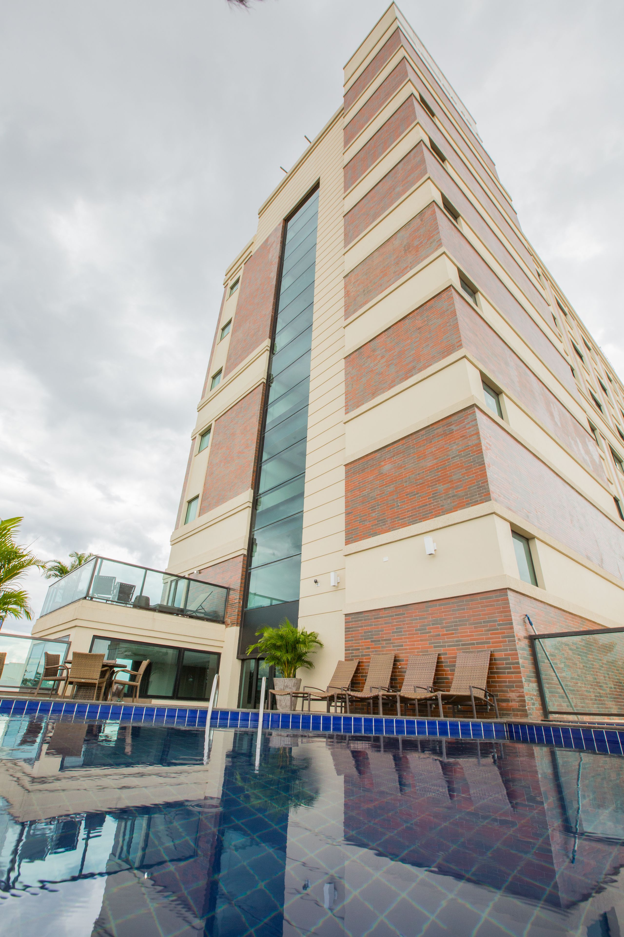 A multi-story hotel with a pool area, glass railings, and outdoor seating.