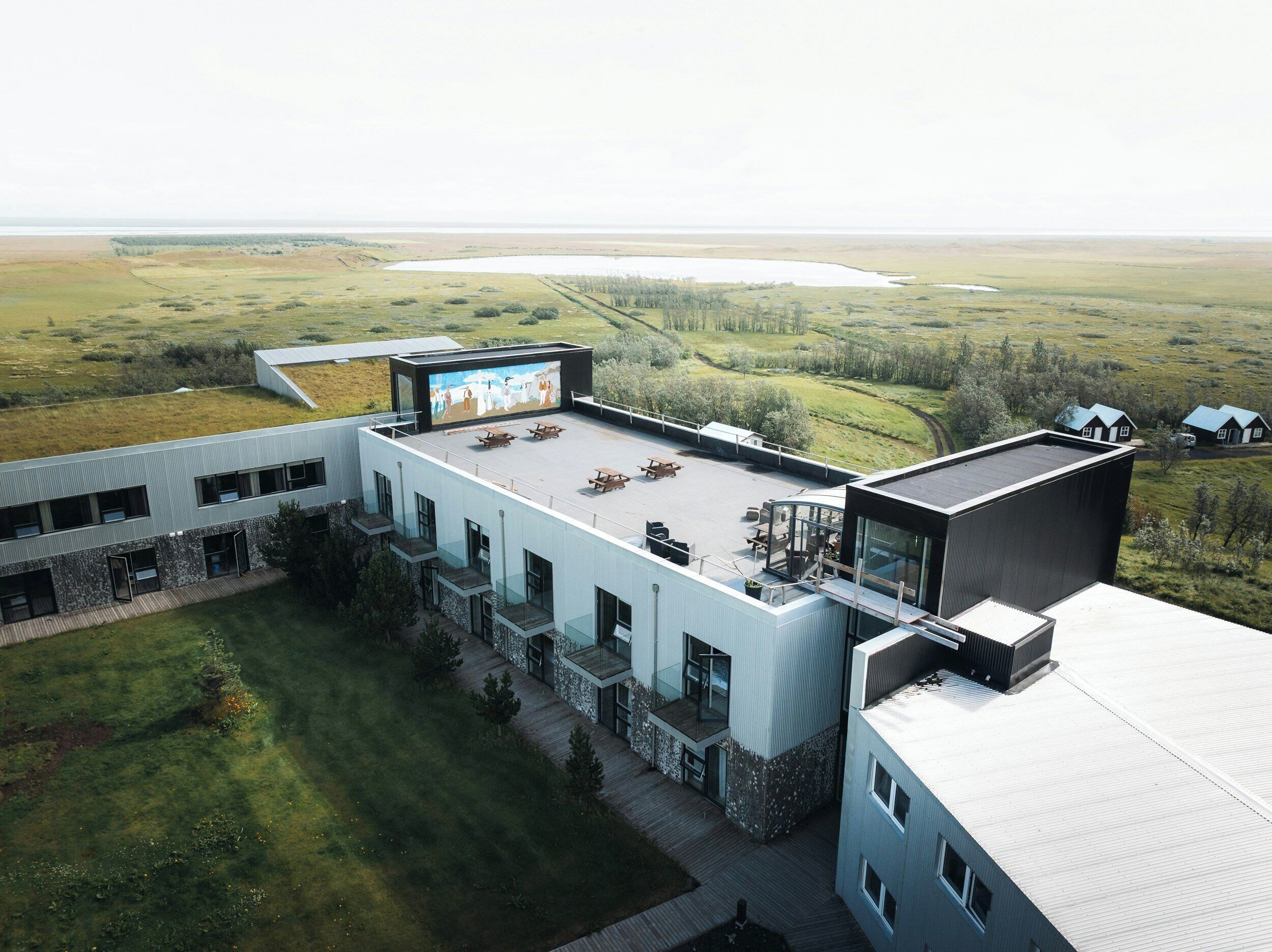 A modern building with a flat roof, outdoor seating area, and a large mural.