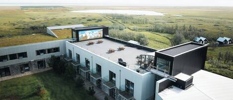 A modern building with a flat roof, outdoor seating area, and a large mural.