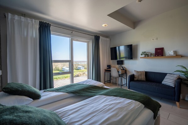 A hotel room with two beds, a desk, a TV, and a sofa.