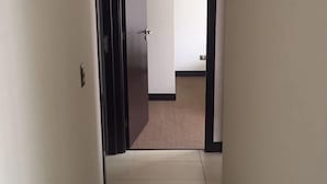 A narrow hallway with a tiled floor leading to a room with a door. - Depto en Iquique Ed. Terranova 1108 (Iquique)