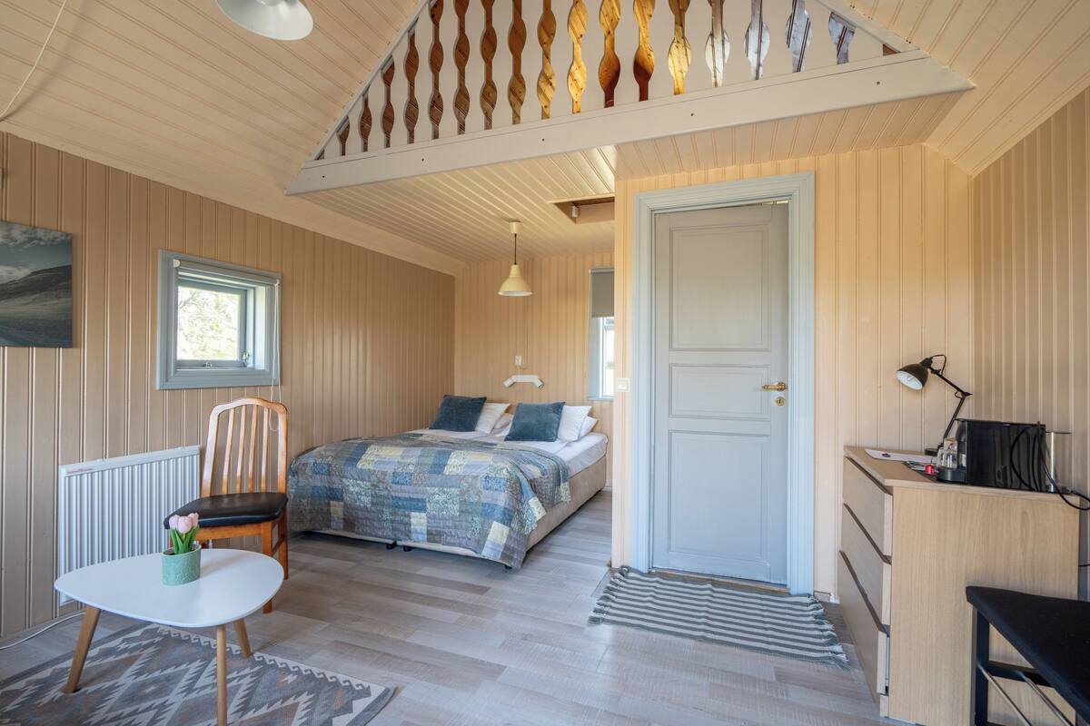 Ein gemütliches Schlafzimmer mit Bett, Sessel, Schreibtisch und Heizkörper.