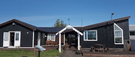 A building with a porch, a covered seating area, and a wooden deck.