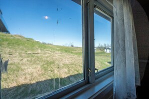 Una ventana con vistas a un campo verde y un edificio a lo lejos.