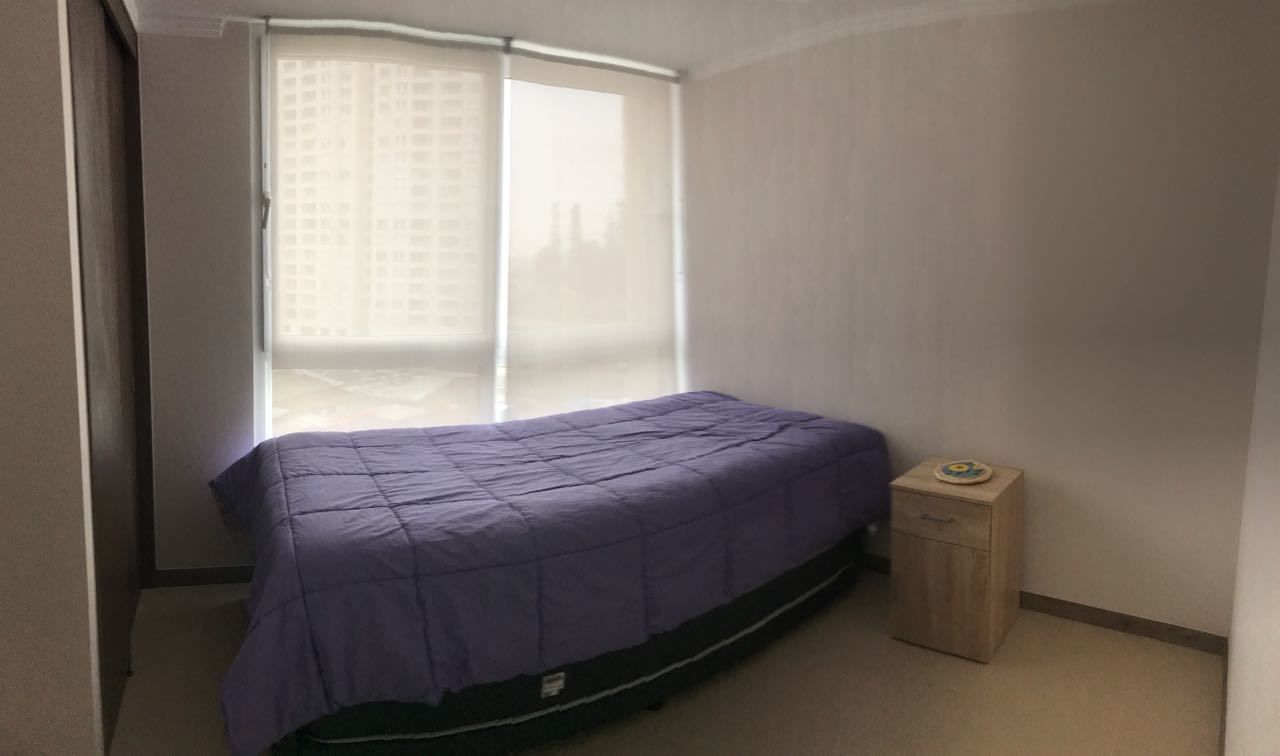 Une chambre à coucher avec un lit, une fenêtre avec des stores et une petite armoire en bois.