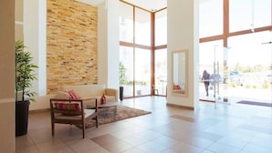 A spacious lobby with a large window, a stone wall, and a seating area with a sofa and a coffee table. - Depto Euro Marina La Serena 1135 (Coquimbo)