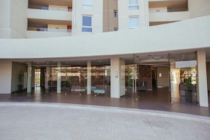 A modern hotel lobby with a glass entrance, seating areas, and a central column. - Depto Euro Marina La Serena 1135 (Coquimbo)