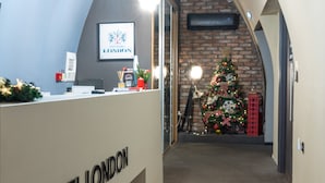 Ein Empfangsbereich mit einem Schild mit der Aufschrift 'HOTEL LONDON', einem Weihnachtsbaum und einer roten Telefonzelle.