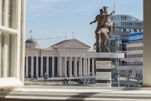 Vista de un edificio con arquitectura clásica, que incluye columnas y una estatua sobre un pedestal.