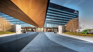 A modern building with a glass facade and a wooden overhang. - Renaissance Warsaw Airport Hotel, an Marriott International (Warsaw)