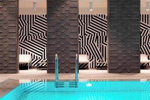 A modern indoor pool area with geometric patterned walls, a clear pool, and lounge seating. - Renaissance Warsaw Airport Hotel, an Marriott International (Warsaw)
