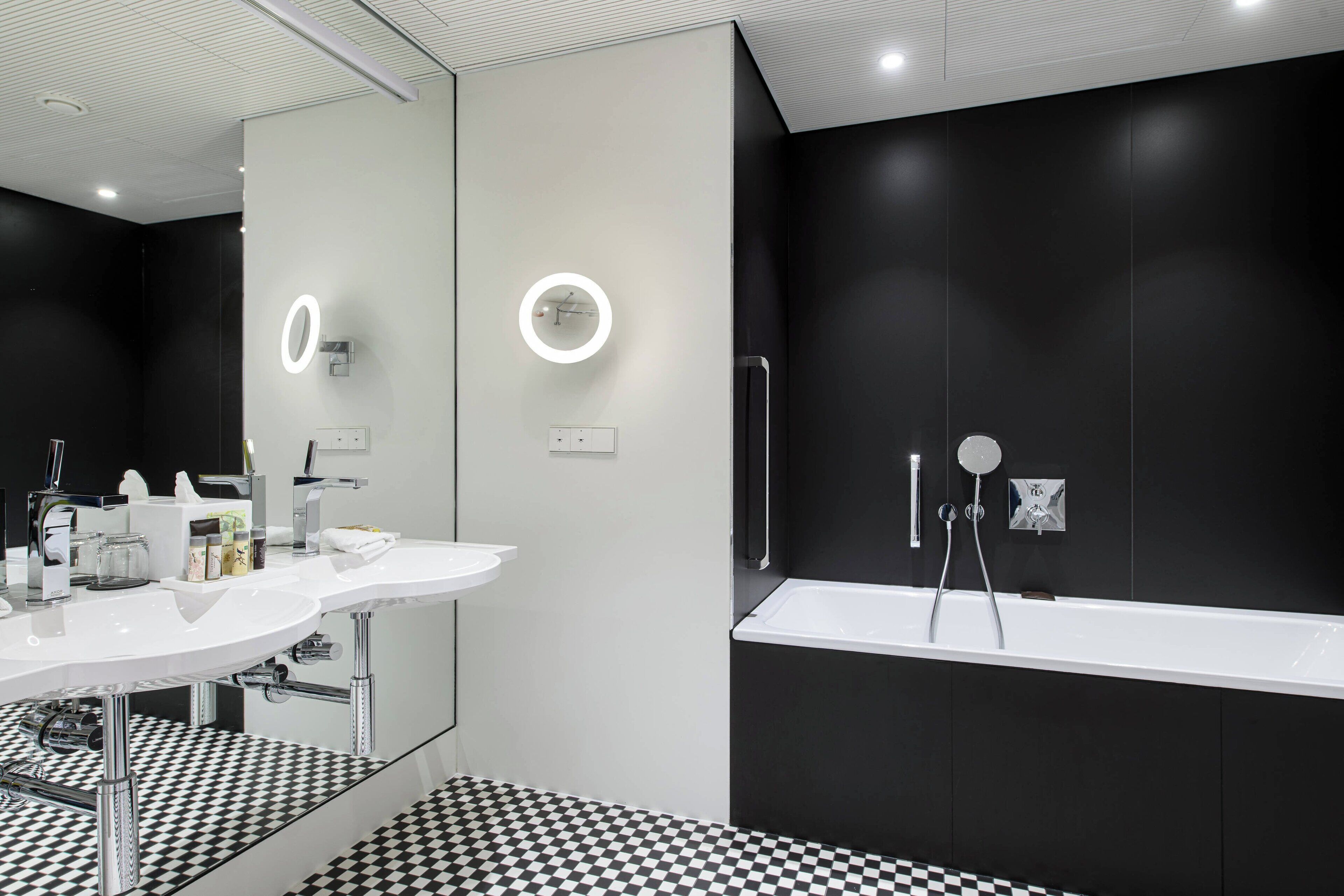Une salle de bain moderne avec deux lavabos, un grand miroir et une baignoire.