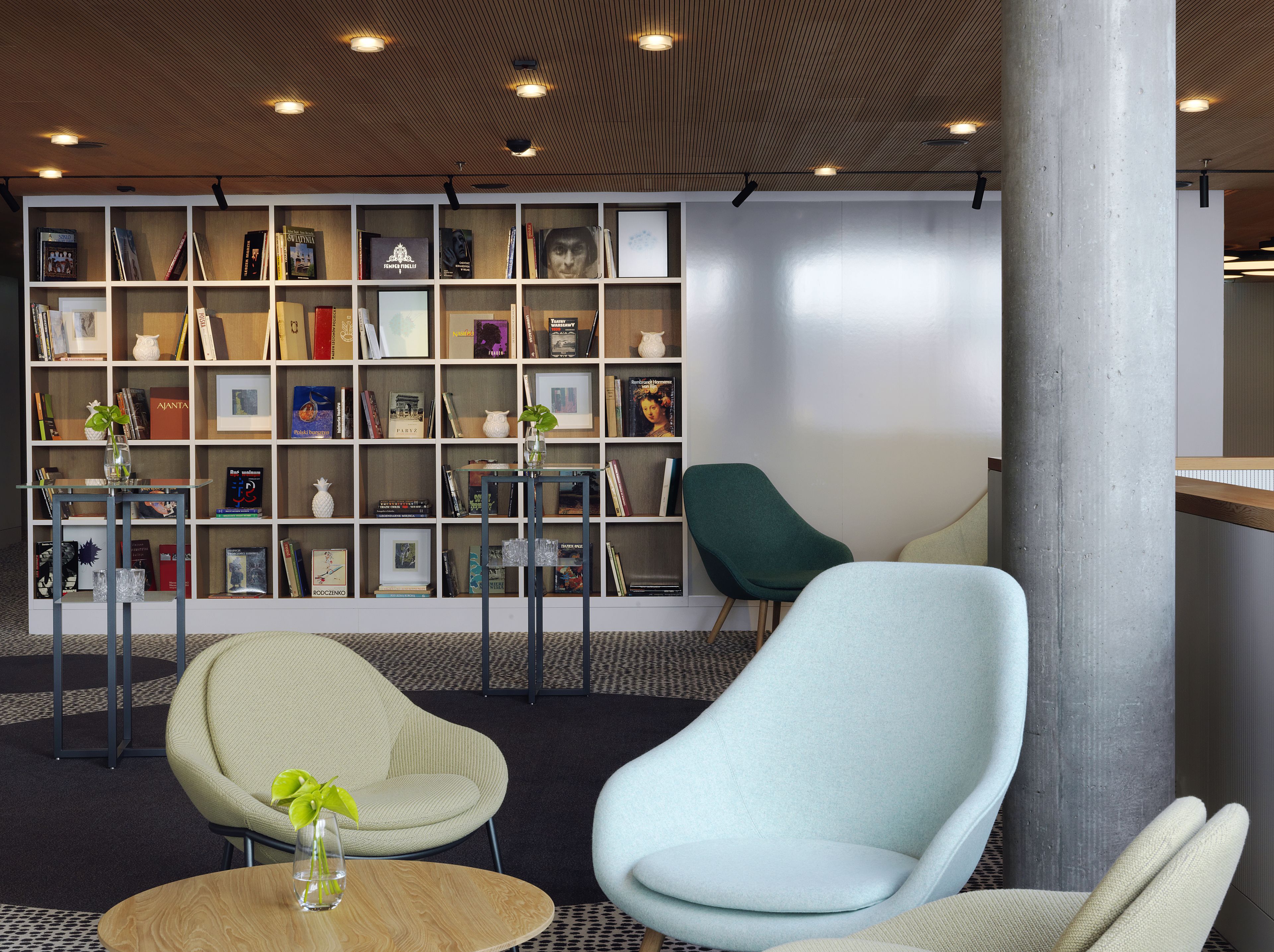 Uma biblioteca moderna com estantes, duas cadeiras e uma mesa de centro.