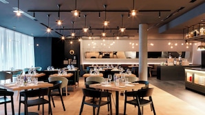 A modern restaurant with multiple dining tables, black chairs, and pendant lighting. - Renaissance Warsaw Airport Hotel, an Marriott International (Warsaw)