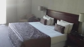 A hotel room with a large bed, a chair, a bedside table, and a lamp. - Welkom INN (Welkom)