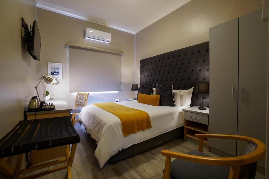 Habitación de hotel con cama, mesitas de noche, escritorio, silla y armario.