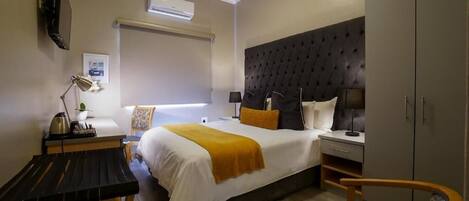 Habitación de hotel con cama, mesitas de noche, escritorio, silla y armario.