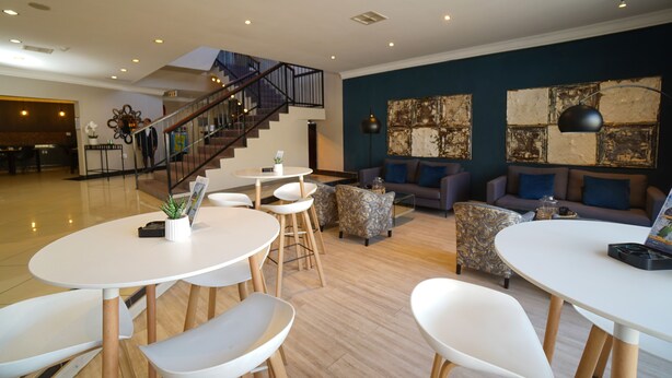 A spacious living area with a staircase, a sofa set, and a coffee table. - The Gallagher Hotel (Midrand)