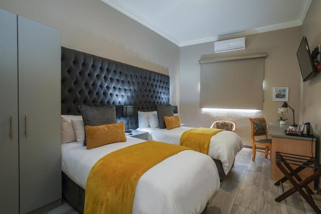 Habitación de hotel con dos camas, un escritorio, una silla y un armario.