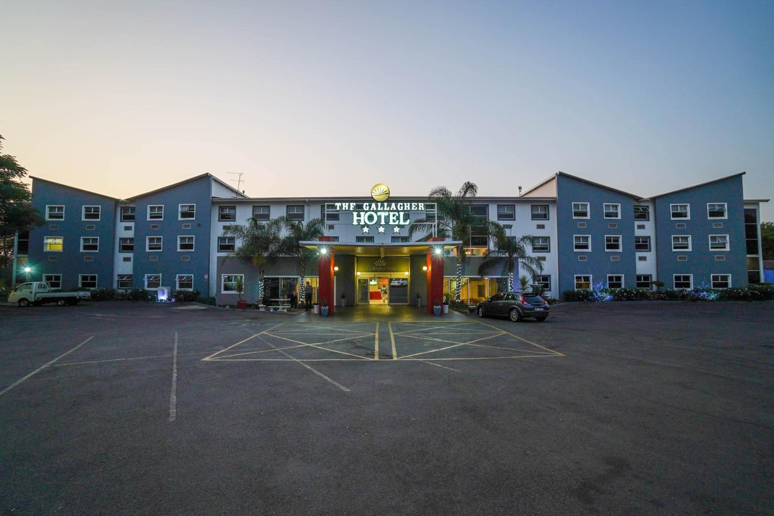 Un hotel con un cartello ben visibile, diversi piani e un parcheggio.