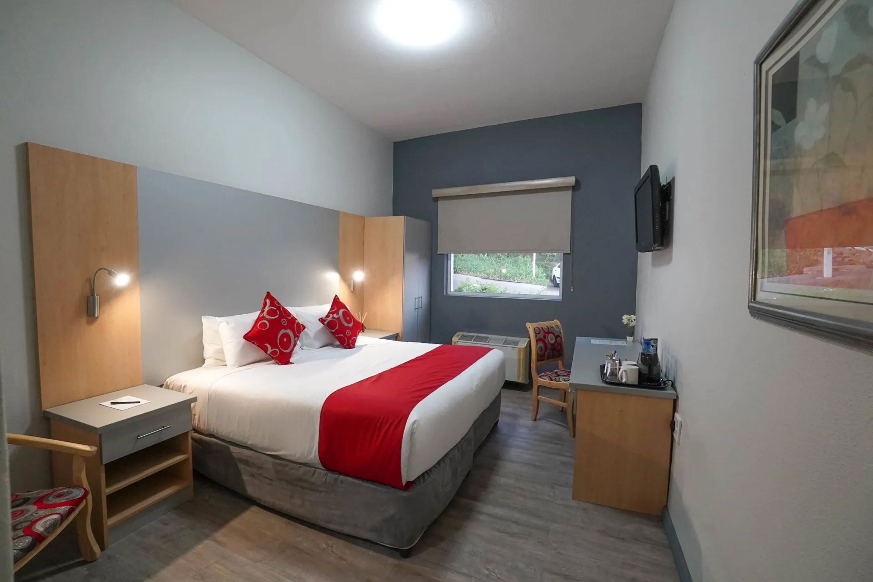 Une chambre d’hôtel comprenant un lit, une table de chevet, une chaise, un bureau et une fenêtre donnant sur un paysage agréable.