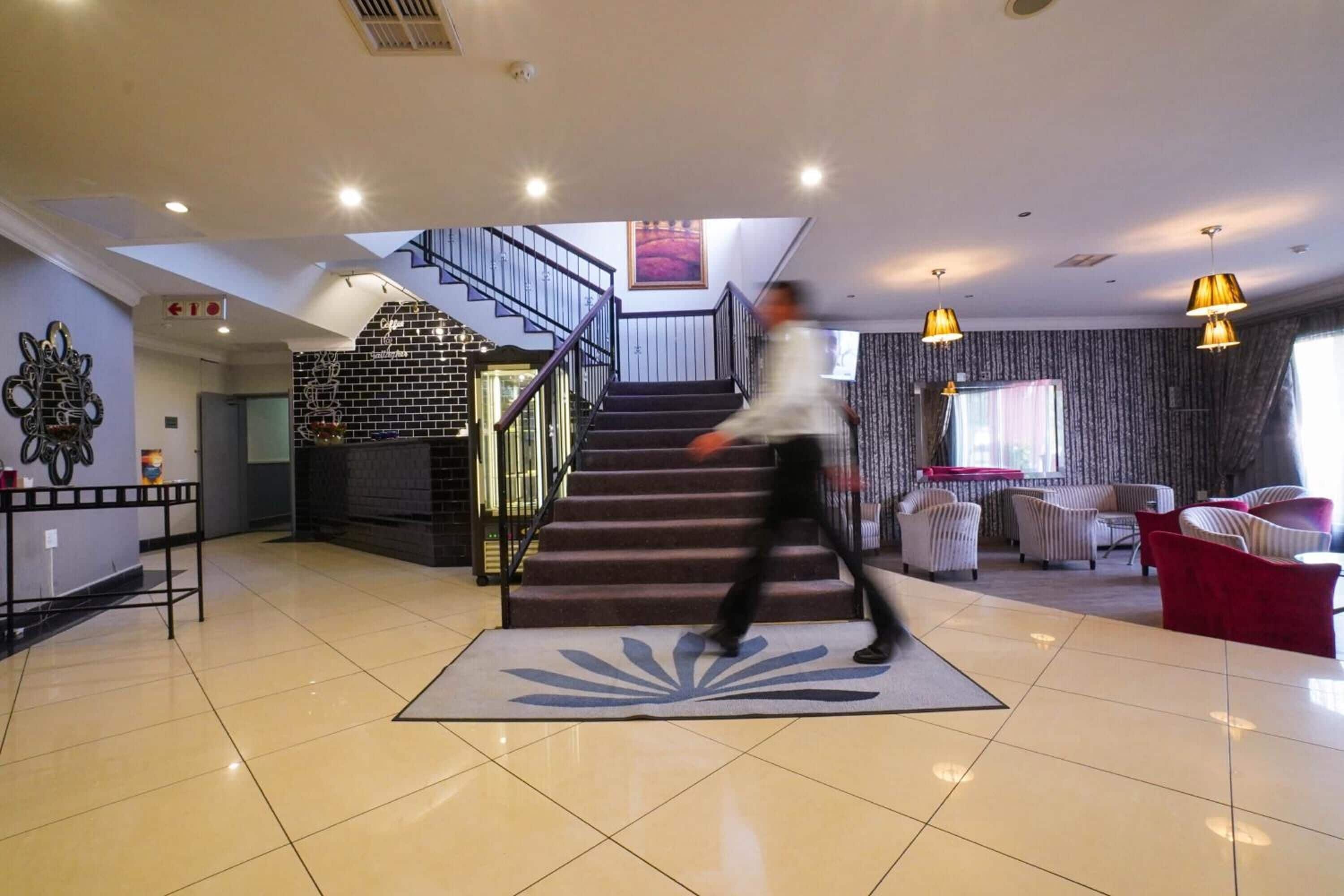 A spacious living area with a staircase, a fireplace, and a seating area with sofas and chairs.