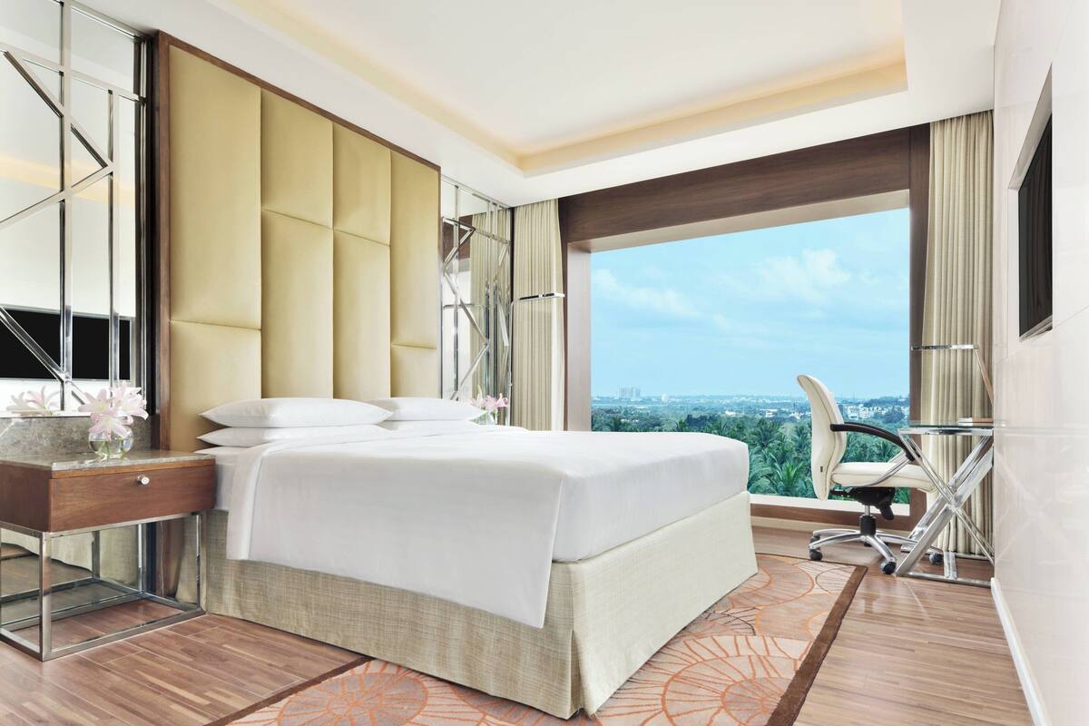 Une chambre d’hôtel moderne avec un grand lit, un bureau, une chaise et une vue sur la ville.