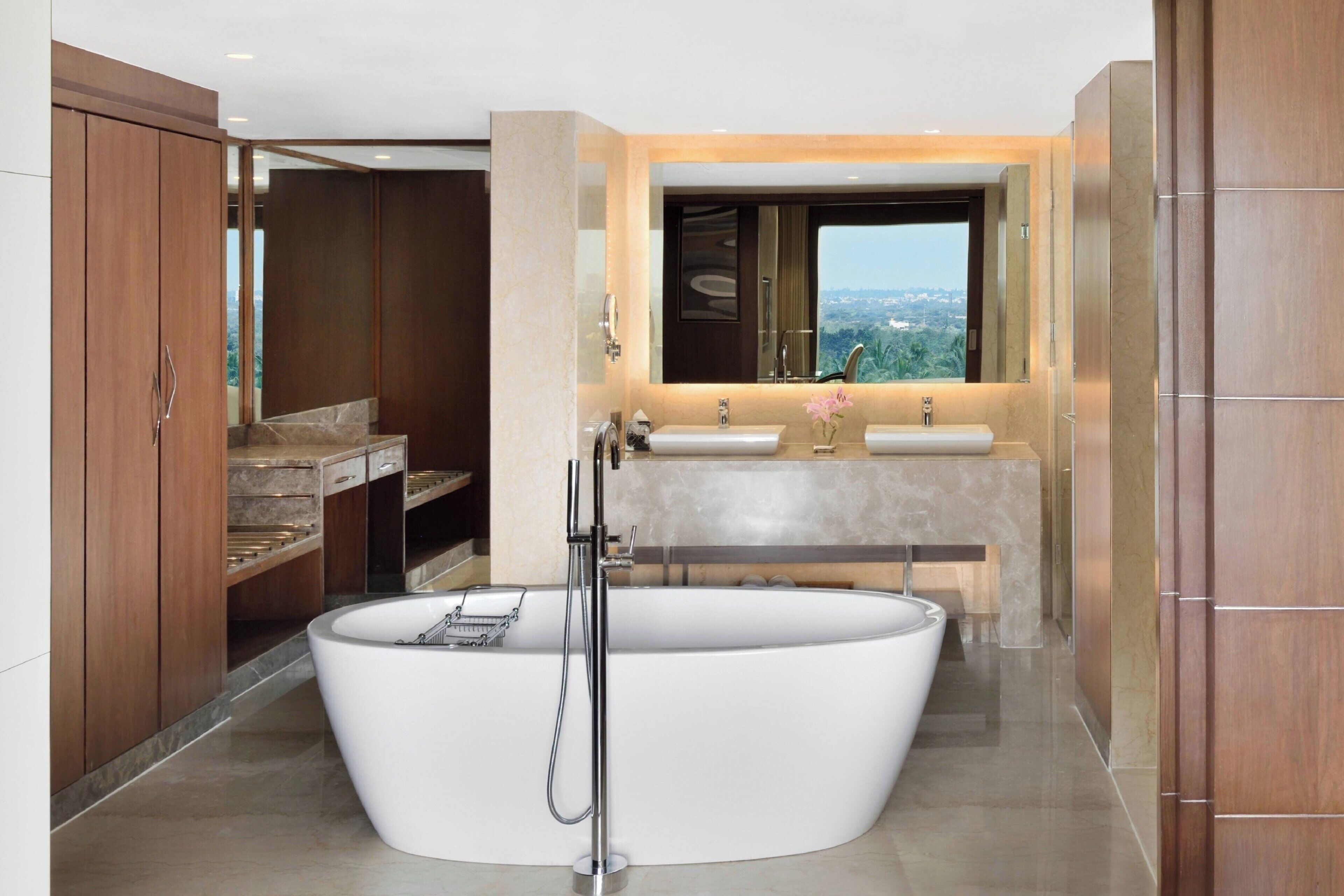 Un baño moderno con una bañera independiente, un lavamanos doble y un espejo grande sobre el lavabo.