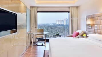 A modern hotel room with a large bed, a flat-screen TV, a desk, and a chair.