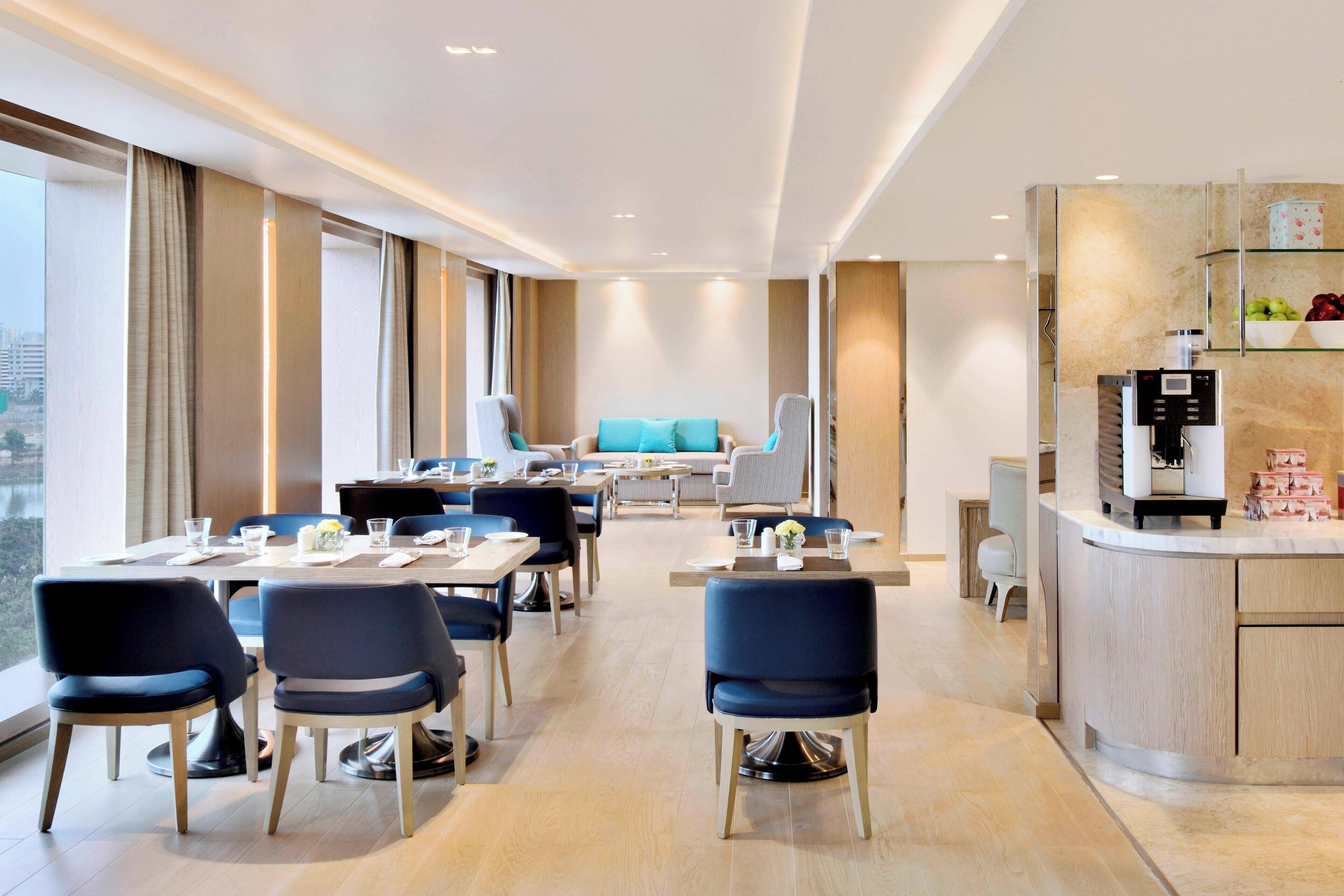 Un comedor de hotel moderno con mesas, sillas y una barra de cocina.