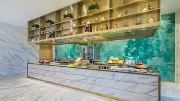 Welcome to our lobby, featuring a reception desk and decorative shelves with plants, ceramic pieces, and sculptures.