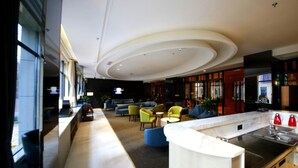 A modern hotel lobby with a central seating area, a kitchen counter, and large windows. - Howard Johnson Life Geckor Zhu (Zhuzhou)