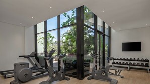 A modern gym with cardio machines, weight benches, and a TV on the wall. - Holiday Inn Nairobi Two Rivers Mall by IHG (Nairobi)