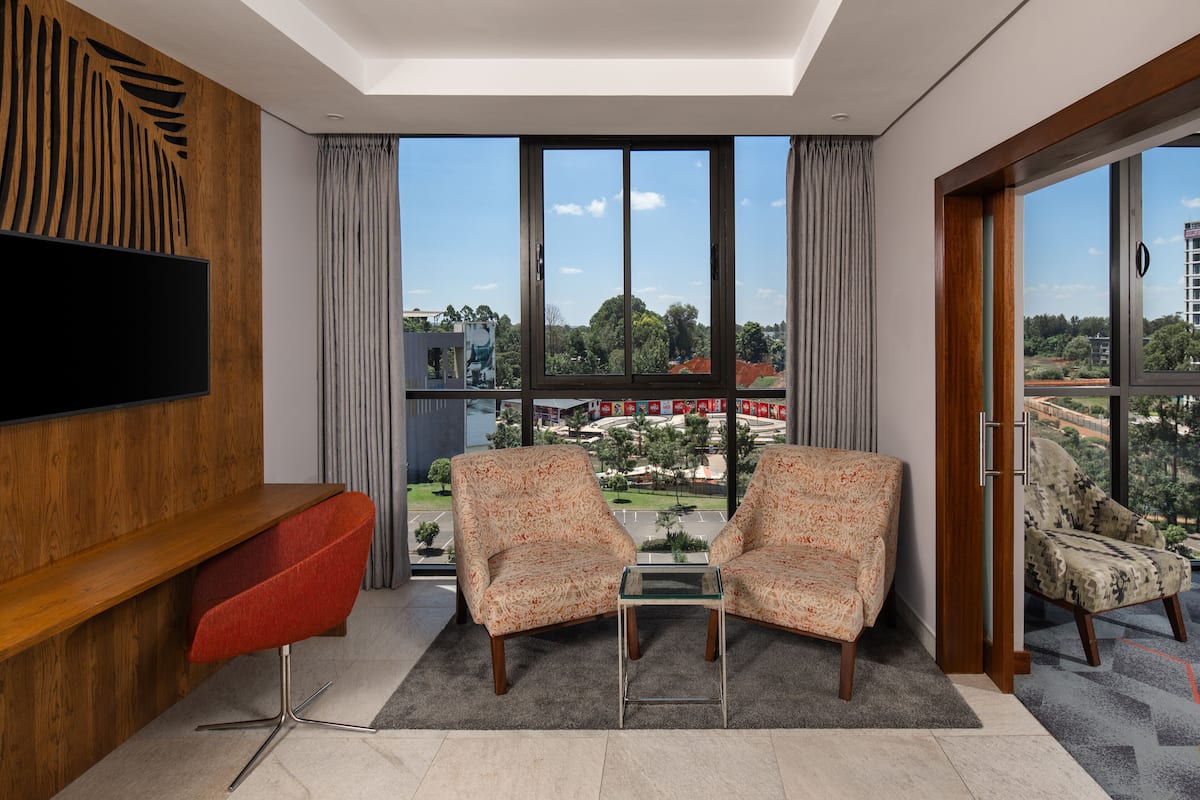 A modern living room with a large TV, two patterned armchairs, and a red chair.