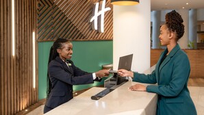 A reception area with a wooden wall and a modern desk. - Holiday Inn Nairobi Two Rivers Mall by IHG (Nairobi)