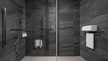 A modern bathroom with a glass-enclosed shower, a hand dryer, and a towel rack.