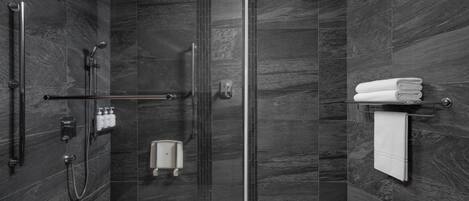A modern bathroom with a glass-enclosed shower, a hand dryer, and a towel rack.